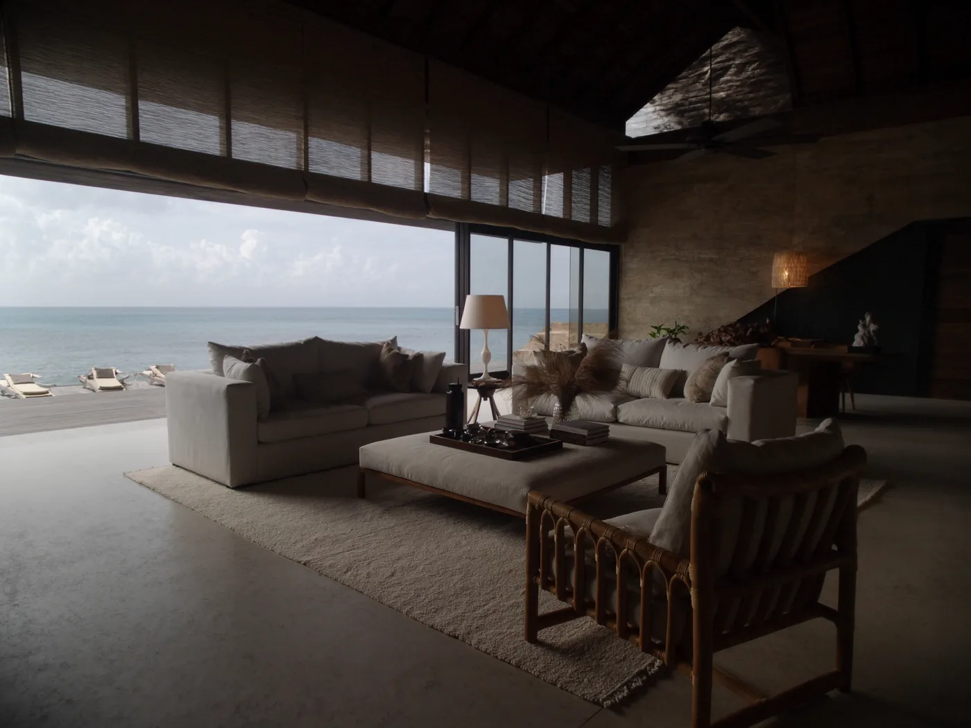 Sala de estar de villa de lujo abierta al mar, con lino, ratán y madera